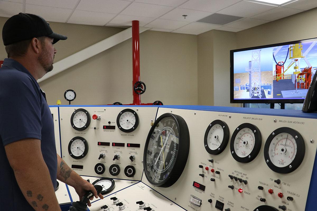 Oilfield worker standing at multi control panel